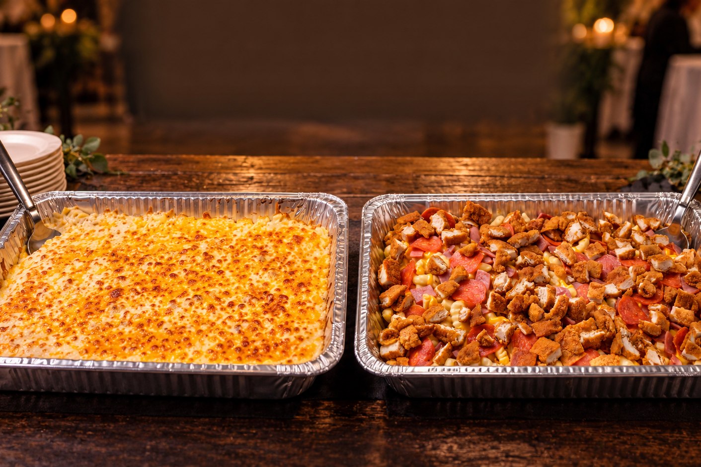 Two catering trays of baked mac and cheese and loaded pasta on a banquet table